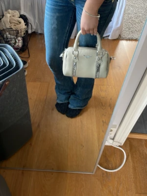 Beige handväska från Don Donna - Snygg beige handväska  i läderimitation med silverfärgade detaljer och dubbla dragkedjor framtill. Väskan har både handtag och en justerbar axelrem för olika stilar. Perfekt storlek köpt för 400kr