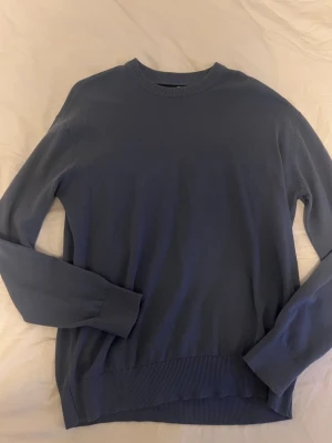 Mörkblå stickad tröja - En stilren mörkblå stickad tröja med rund halsringning och ribbade muddar vid ärmslut och nederkant. Tröjan har en klassisk passform och är perfekt för lager på lager. Materialet känns mjukt och bekvämt mot huden.