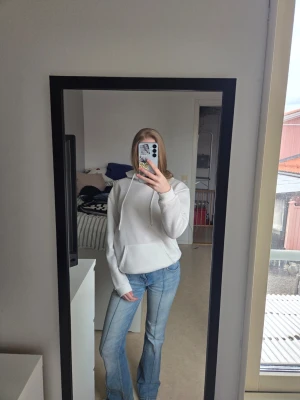 Vit hoodie med huva och ficka - Säljer en enkel och clean vit hoodie med huva och dragsnören. Hoodien har en stor magficka och ribbade muddar vid ärmar och nederkant. Perfekt till jeans eller mjukisbyxor för en avslappnad look. Storleken är XS men skulle säga XXS