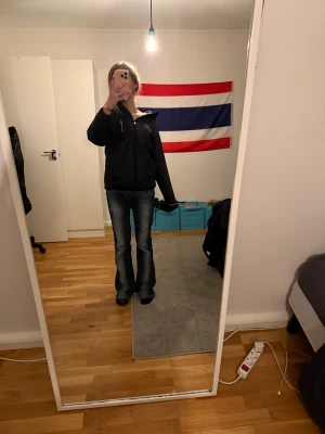 Svart vindjacka Sail Antarctica - Snygg svart vindjacka från Sail Antarctica med dragkedja och hög krage. Jackan har logga och text på bröstet samt praktiska fickor. Perfekt för blåsiga dagar och enkel att matcha med olika outfits.