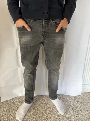 Svarta slim fit jeans från dondup med tvättad look - Säljer ett par svarta slim fit jeans från dondup med snyggt tvättad effekt och klassisk femficksmodell. Jeansen har normal midja och smal passform hela vägen ner. Perfekta för dig som gillar en avslappnad men ändå stilren look. Storleken är w30