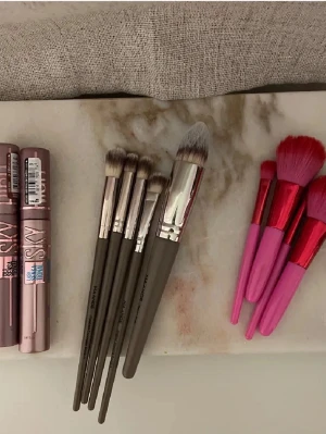Allt i bilden för 400 - Säljer ett set med sminkborstar från MAKEUP ME. Borstarna har mjuka syntetiska borst, några med gråa handtag och silverdetaljer, andra i rosa och rött. Perfekta för både ögonskugga och bas. Snygg design som gör sminkrutinen roligare.