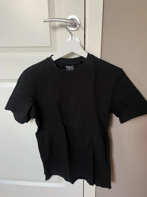 Svart Jack & Jones t-shirt i bomull - En klassisk svart t-shirt från Jack & Jones med rund hals och enkel design. Tillverkad i mjuk bomull som känns skön mot huden. Perfekt basplagg för alla tillfällen och lätt att matcha med andra kläder.