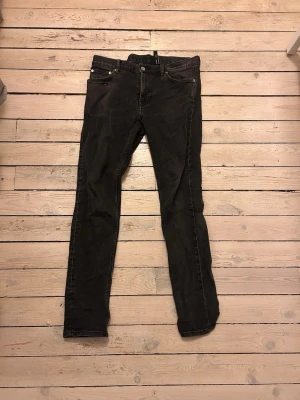 Svarta slim fit jeans - Säljer ett par svarta slim fit jeans med klassisk femficksdesign och dragkedjegylf. Jeansen har smal passform och raka ben, perfekta för en clean och stilren look. Materialet är mjukt och stretchigt för extra komfort.