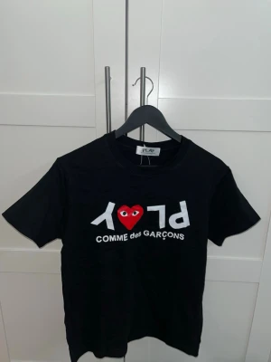 Svart t-shirt från Comme des Garçons - Asfet t-shirt från Comme des Garçons Play med vit text och ett rött hjärta med ögon på bröstet, toppenskick. 🛑Skriv vid funderingar.                  🛑Snabb affär=kan gå ner i pris