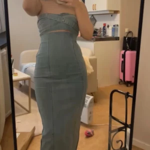  axelbandslös jeansklänning -  axelbandslös jeansklänning med figurnära passform och markerad midja. 