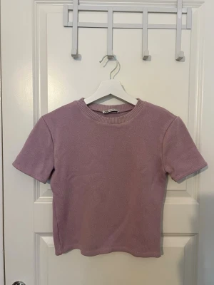 Ljuslila stickad kortärmad topp - Supersöt ljuslila stickad topp med korta ärmar och rund hals. Perfekt till jeans eller kjol för en chill och trendig look. 