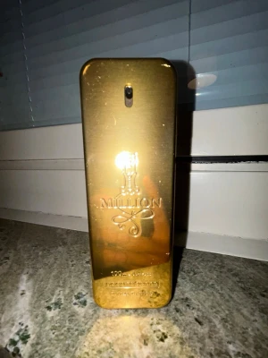 Paco Rabanne 1 Million Eau de Toilette - Säljer en ikonisk Paco Rabanne 1 Million parfym i den klassiska guldfärgade flaskan som liknar en guldtacka. Flaskan har en elegant kombination av guld och svart och är tillverkad i metall och plast. Doften är känd för sin lyxiga och maskulina karaktär. Ca 80% kvar.
