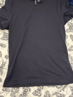 Mörkblå basic t-shirt från Weekday - En enkel och stilren mörkblå t-shirt från Weekday. T-shirten har korta ärmar, rund halsringning och är tillverkad i mjuk bomull. Perfekt för en clean och avslappnad look.