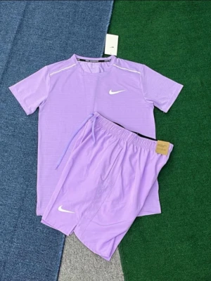 Nike miller short set Lila - Säljer ett par lila Nike shorts med vit logga och snörning i midjan. Shortsen har en sportig look och är tillverkade i ett lätt och bekvämt syntetmaterial, perfekta för träning eller avslappnade dagar.