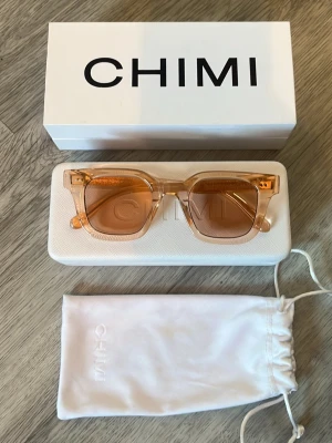 Chimi solglasögon   - Snygga solglasögon från Chimi med transparent orange båge och matchande tonade glas. Modellen har en fyrkantig form och levereras med originalfodral, box och tygpåse. Perfekt accessoar för att lyfta din stil. Hör av dig vid frågor, allt gott! 