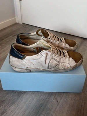 Philippe Model sneakers  - Säljer ett par Philippe Model Paris sneakers i beige mocka och läder med bruna detaljer på tå och plös samt svart hälparti. Klassisk låg modell med vita snören och diskret logga på sidan. Perfekta för dig som gillar en avslappnad och trendig stil. Som ni ser på bilden finns det goda tecken på användning, vilket avgör det nedsatta priset. Originalpris: 3100. Hör av er vid frågor, allt gott!