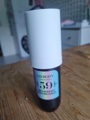 Airbody 59 Vanilj Orkidé & Viol Parfym - Airbody parfym i doften 59 Vanilja Orkidé & Viol. Flaskan är cylinderformad med vit kork och holografisk etikett. Innehåller 50 ml och har en modern, stilren design som passar perfekt i väskan. Doften kombinerar söta och blommiga toner.