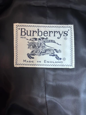 Äkta Burberry rock - Säljer en fin och äkta Burberry rock som har endast 5 knappar och en trasig men om du är bra på slöjd kan du frixa den trasiga! Bäst under vår, höst och vinter säsongen eftersom den håller dig varm! För damer. Säljer för att ja behöver pengar och en den passar inte min syster längre. Om du vill köpa en utan skador blir det ungefär 3-4000kr och helt nytt är runt 20-30 000kr! Gärna möts i Gullmarsplan i Stockholm!