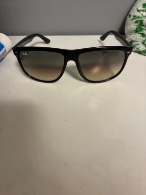 Svarta Ray-Ban solglasögon boyfriends 4147 - Snygga svarta solglasögon från Ray-Ban med klassisk wayfarer-form. Bågarna är svarta och glasen har en mörk toning som går från mörkt upptill till ljusare nedtill. Perfekta för soliga dagar och ger en cool vibe till din outfit.