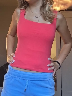 Rosa ärmlös linnetopp - Snygg rosa linnetopp med breda axelband och rak halsringning. Toppen är figurnära och har en enkel, stilren design som passar perfekt till jeans eller kjol. Tillverkad i mjukt bomullsmaterial som känns skönt mot huden.
