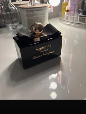 Signorina Misteriosa parfym - Signorina Misteriosa från Salvatore Ferragamo är en elegant parfym i en svart, rektangulär glasflaska med gulddetaljer och en stor svart rosett. Flaskan har en rund guldfärgad kork som ger en lyxig känsla. Perfekt för dig som gillar exklusiva dofter och snygg design. 100 ml, skriv om ni vill ha bild på vad den ska dofta 