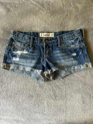 Blå korta lågmidjade jeansshorts från Hollister - Snygga blå jeansshorts från Hollister. Midjemått ca 38 cm