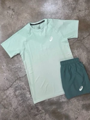 Mintgrönt träningsset från Asics - Snyggt träningsset från Asics med en mintgrön t-shirt och matchande shorts i mörkare grön nyans. Båda plaggen har Asics-logga framtill och är tillverkade i ett lätt, snabbtorkande material som passar perfekt för löpning eller gym.