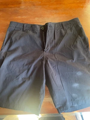 Mörkblå shorts från 157, storlek XXL - Säljer ett par mörkblå shorts från 157 i storlek XXL. Klassisk modell med fickor på sidorna, bälteshällor och dragkedja framtill. Perfekta för varma dagar och enkla att matcha med olika stilar. Endast testade saknar prislapp