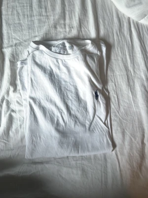 Vit t-shirt med logga - Klassisk vit t-shirt med rund hals och liten broderad logga på bröstet. Enkel och stilren design som passar till det mesta. Tillverkad i mjuk bomull för skön känsla hela dagen.