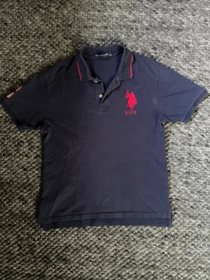 Polo assassin - Säljer en US polo i okej skick! Storlek L i barn så passar xs/s! Tveka inte att skriva vid minsta fundering😁
