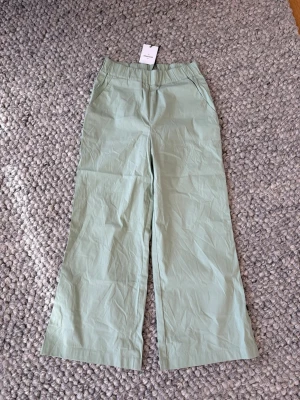Ljusgröna linnebyxor Gina Tricot - Ljusgröna byxor från Gran Sasso med bred resår i midjan och raka, vida ben. Byxorna har sidfickor och är gjorda i ett tunt, luftigt material som passar perfekt för varma dagar. Enkel och stilren design som är lätt att matcha. Italiensk 38:a (34:a I EU) nypris: 2499kr