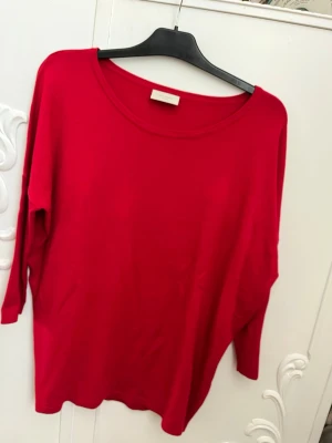 Röd långärmad topp i bomull - En enkel och stilren röd långärmad topp med rund halsringning. Tillverkad i mjuk bomull, perfekt för en avslappnad look. Toppen har en söm längs ryggen som ger en snygg detalj.