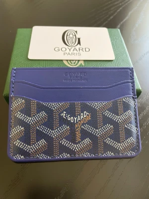 Blå kortfodral från Go4yard - Snyggt blått kortfodral från Go4yard med klassiskt mönster i blått, vitt och brunt. Tillverkat i läder med flera kortfack och präglad logotyp framtill. Perfekt för dig som vill ha en stilren och exklusiv accessoar i fickan.