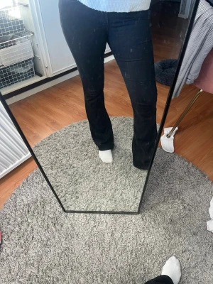 Svarta bootcut jeans - Säljer ett par svarta bootcut jeans med klassisk femficksdesign och normal midja. Jeansen har en snygg utsvängd passform nertill och är perfekta för dig som gillar en tidlös look. Materialet är stretchigt och bekvämt. Lite solblekta, se bilder. Låg midja.