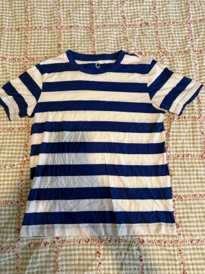 Randig blåvit t-shirt från Cubus  - Snygg t-shirt med breda blå och vita ränder från Cubus. Klassisk rund halsringning och korta ärma. Tillverkad i mjuk bomull.