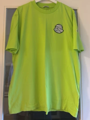Grön Moncler t-shirt med logga - Unik  grön t-shirt från Moncler med unik broderad logga på bröstet. T-shirten har klassisk passform och rund hals. Perfekt för dig som vill sticka ut med en färgstark look.
