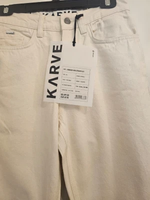 Vita raka jeans från Karve small packet - Snygga vita jeans från Karve med rak passform och klassisk femficksdesign. Jeansen har hög midja och är tillverkade i ett kraftigt bomullstyg. Perfekta för en clean och stilren look.