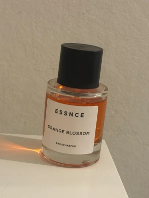 ESSNCE Orange Blossom parfym - Fräsch Eau de Parfum från ESSNCE med doften Orange Blossom. Flaskan är rund och gjord av glas med en svart matt kork. Parfymen har en tydlig orange färg som ger ett stilrent intryck. Perfekt för dig som gillar blommiga och fruktiga dofter. Använd ett fåtal gånger. 