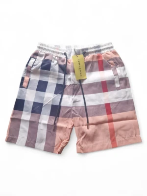 Burberry shorts - Snygga shorts från Burberry med klassiskt rutigt mönster i svart, vitt, rött och beige. De har elastisk midja med snörning och sidofickor. Perfekta för sommaren och ger en trendig look.