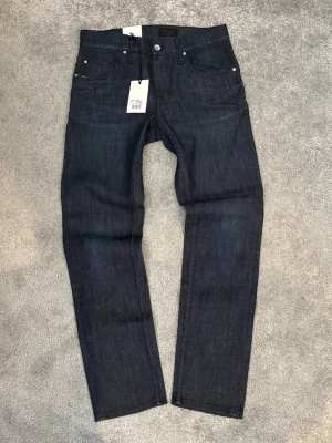 Mörkblå raka jeans från Tiger of Sweden - Snygga mörkblå jeans från Tiger of Sweden i rak modell. Jeansen har klassisk femficksdesign, silverfärgade nitar och knapp, samt etikett bak i midjan. Tillverkade i kraftigt denimtyg som ger en stilren och tidlös look.