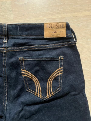 Mörkblå Hollister jeans - Snygga mörkblå low waist jeans från Hollister som är helt oanvända. Bakfickan har dekorativa sömmar och tillverkade i mjukt denimtyg. Skriv vid minsta fundering!🌸