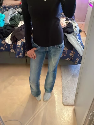 Svart långärmad topp med diskret detalj - Säljer en svart långärmad topp med tight och skönt material samt bra passform och en liten diskret detalj med stenar på bröstet. Toppen har en enkel och clean look som är lätt att matcha med olika stilar. Materialet känns mjukt och stretchigt. Enkel att ha till både ideottslektionen eller som underställ. Har ett litet hål som knappt syns
