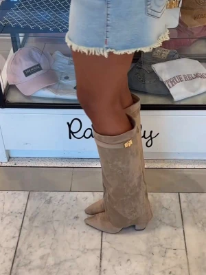 Beige/brun mockastövlar från raglady  - Snygga beige stövlar i mocka med en dekorativ gulddetalj vid skaftet. Stövlarna har en spetsig tå. Så otroligt fina till sommaren 