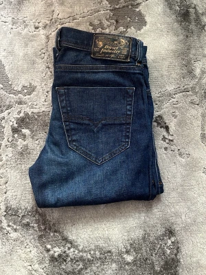 Mörkblå jeans från Diesel - Snygga mörkblå jeans från Diesel med klassisk femficksmodell och raka ben. Jeansen har en diskret tvätt och detaljerad bakficka samt Diesel-logga på bakre linningen. Tillverkade i ett mjukt och slitstarkt denimtyg som sitter skönt hela dagen.