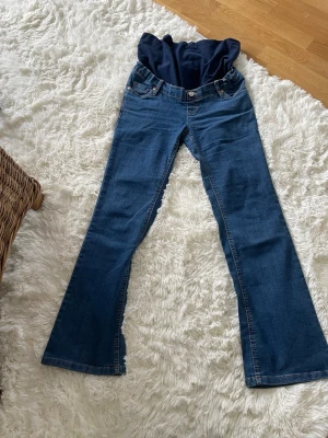 Mammabyxa bootcut från Bonprix - mammabyxpr från Bonprix  och stronger med mjuk stretchig mudd över magen. Klassisk femficksmodell i denim med bekväm passform och utsvängda ben. Perfekt för dig som vill ha jeans-look och snygga sköna tränings thights under graviditeten.