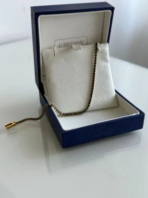 GULDPLÄRERAD TENNISARMBAND  - Armband i guldpläterad guld i tennismodell. Storleken är mellan 17/18. Box medföljer ej med. Köpt från Guldfynd, nypris 399kr. Stämpel finns.