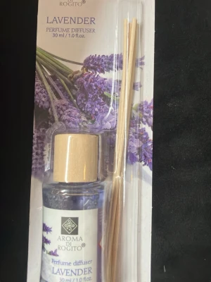 Lavendel doftpinnar Aroma di Rogito - Lavendel doftpinnar från Aroma di Rogito. Innehåller en 30 ml glasflaska med lavendeldoftande parfymolja och sex träpinnar för att sprida doften i rummet. Flaskan har ett ljust trälock och förpackningen har ett motiv av lila lavendelblommor.