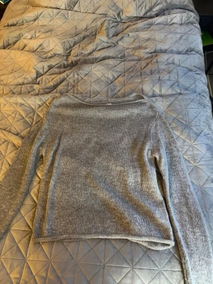 Grå stickad off shoulder tröja från Gina Tricot - Mysig grå stickad tröja från Gina Tricot i ullblandning. Tröjan har en rak passform, långa ärmar och en off shoulder halsringning. Perfekt för en vardagsoutfit och passar till det mesta i garderoben.