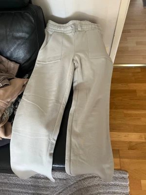 Beige mjukisbyxor med raka ben - Snygga mint gröna mjukisbyxor med raka ben och resår i midjan. Byxorna har två fickor fram och två bakfickor. Perfekta för en avslappnad stil och tillverkade i mjukt material som känns skönt mot huden. dom är helt nya aldrig använda. 