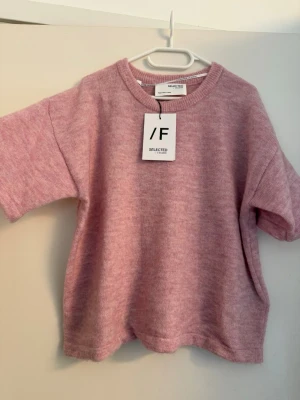 Rosa stickad tröja från Selected Femme - Säljer en söt rosa stickad tröja från Selected Femme. Tröjan har korta ärmar, rund halsringning och en avslappnad passform. Materialet är mjukt och ger en mysig känsla. Perfekt att styla med jeans eller kjol. Nypris:499kr