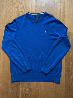 Blå tröja från Polo Ralph Lauren - Klassisk blå tröja från Polo Ralph Lauren med rund halsringning och vit broderad logga på bröstet. Perfekt på en lite kylig sommarnatt och passar perfekt till ett par svarta jeans. Den är väl använd och i väldigt bra skick. Pris kan diskuteras. Skriv om ni undrar något.