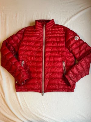 Röd dunjacka från Moncler - Säljer nu denna unika dunjacka från moncler! Funkar perfekt till höst, sommar och vår. Perfekt för dig som vill sticka ut med en fräsch stil. Jackan är i storlek S och i ett utmärkt skick. Hör av dig vid funderingar!