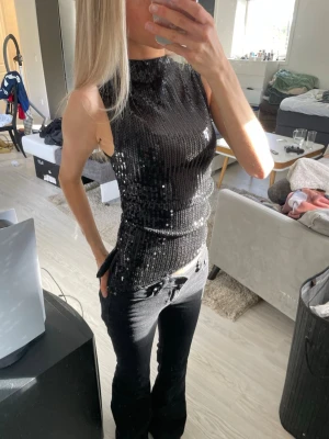 Svart paljettopp med hög hals och slits - Festtopp med glittriga paljetter och insydd med slits på vänster sida. Använd en gång💕
