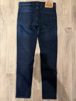 Replay Anbass Jeans Mörkblå W31/L32 - Slim Fit - Replay Anbass mörkblå jeans i stretchig denim med slim fit passform som sitter snyggt och bekvämt och funkar till allt, storlek W31/L32, midja 40 cm, ytterbenslängd 102,5 cm, benöppning 15,5 cm, modellen är 185cm & väger 65kg, i fint skick.